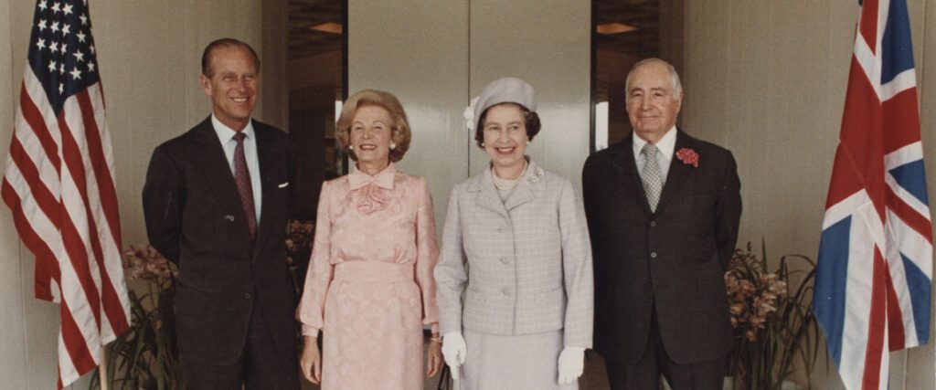 Medium shot of HRH Prince Philp, Leonore Annenberg, HRH Queen Elizabeth II, and Walter Annenberg standing in the Sunnylands entry court in 1983