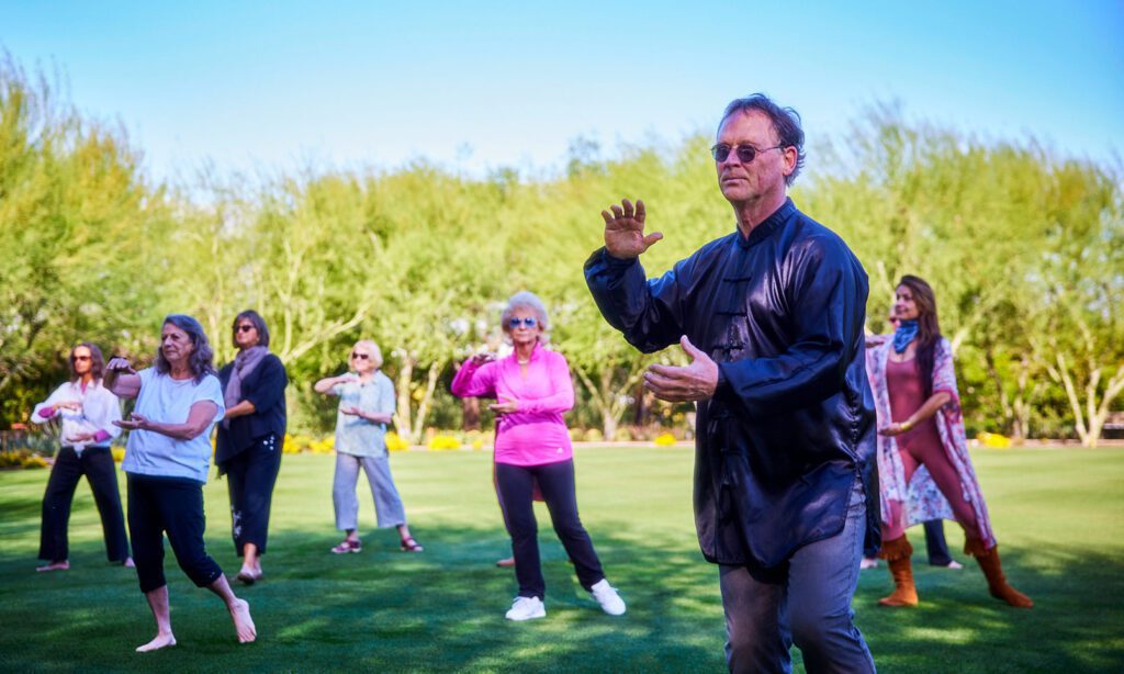 A tai chi instructor practicing with several participants on the Great Lawn at Sunnylands