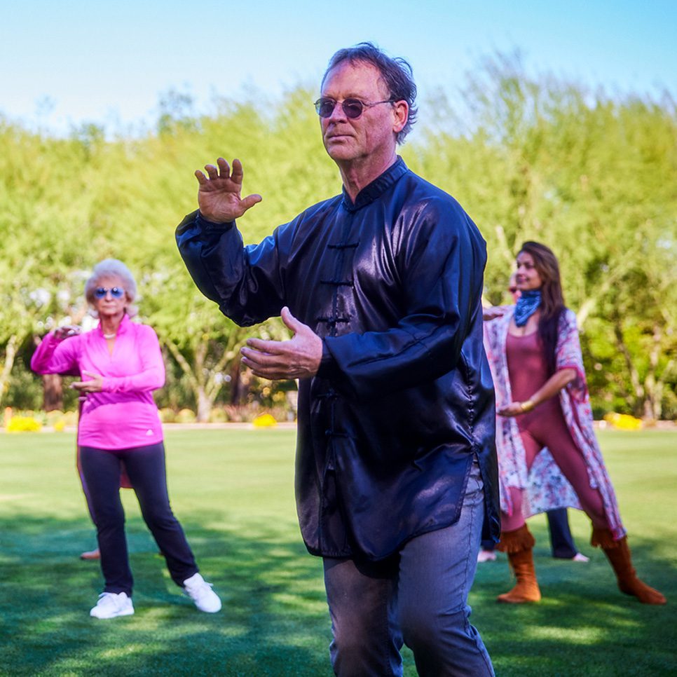 A tai chi instructor practicing with several participants on the Great Lawn at Sunnylands