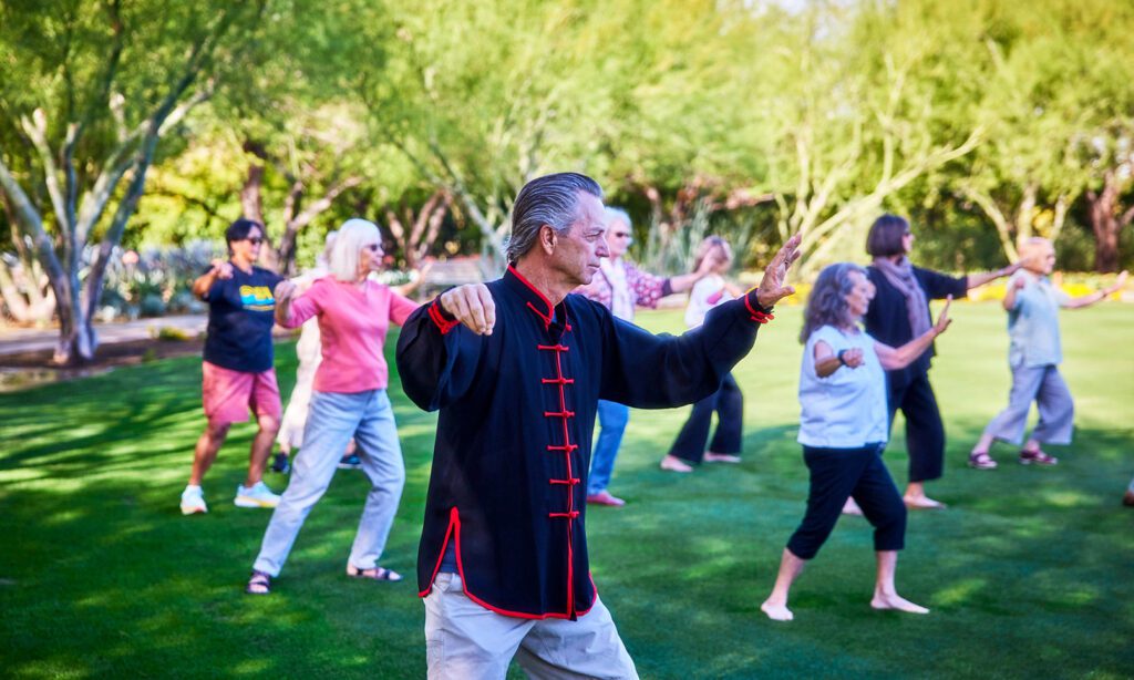 A tai chi instructor practicing with several participants on the Great Lawn at Sunnylands